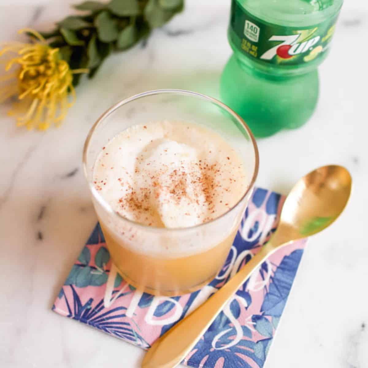 A boozy pineapple float topped with nutmeg in a short cocktail glass.