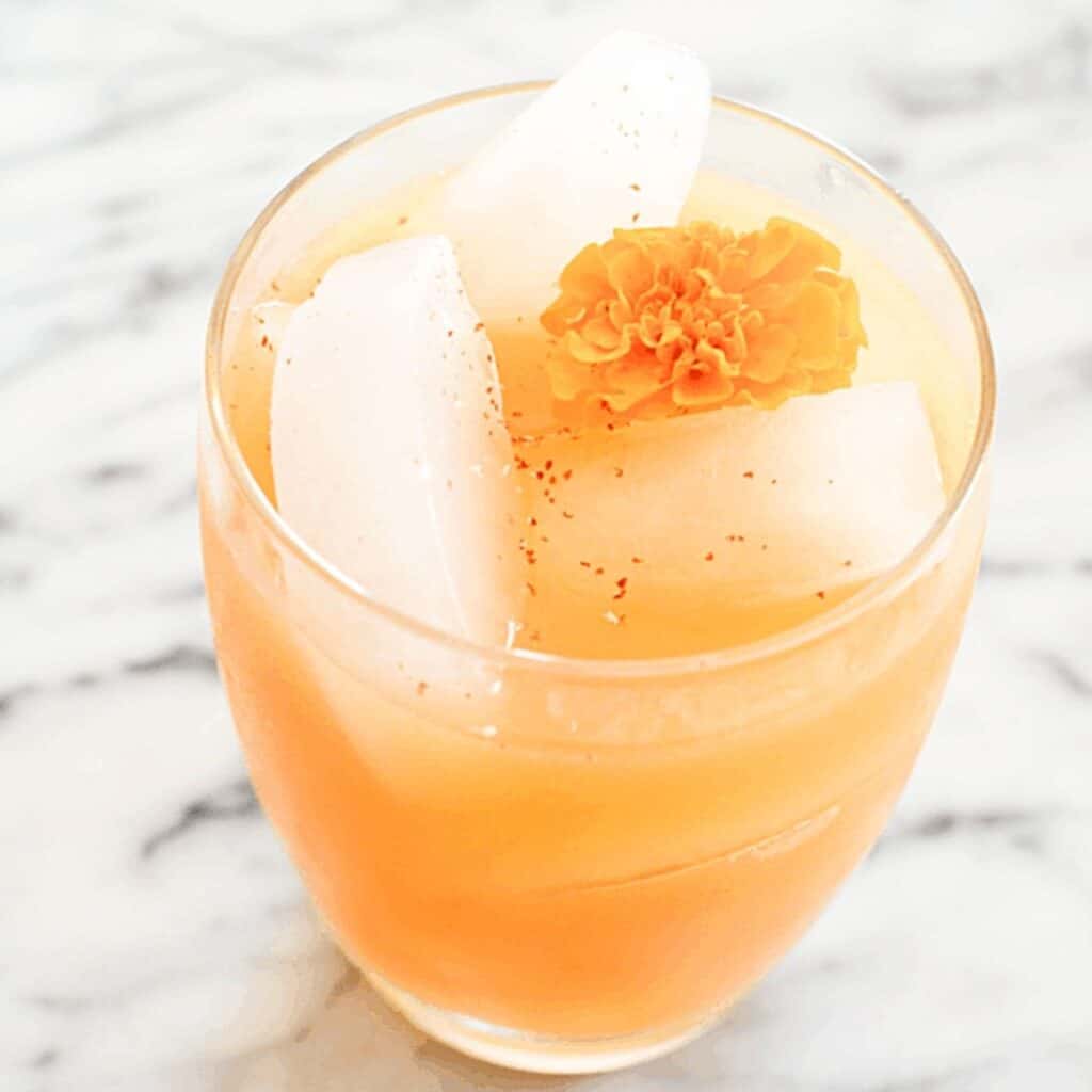 Spiced Pear Cocktail on a counter with an edible flower garnish.