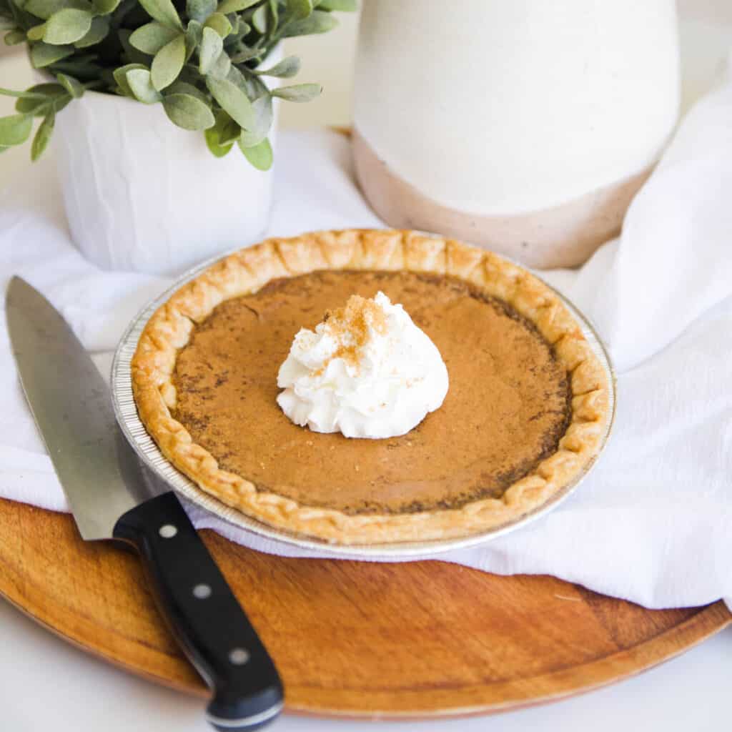 A whip cream topped Brown Sugar Pie next to a knife.