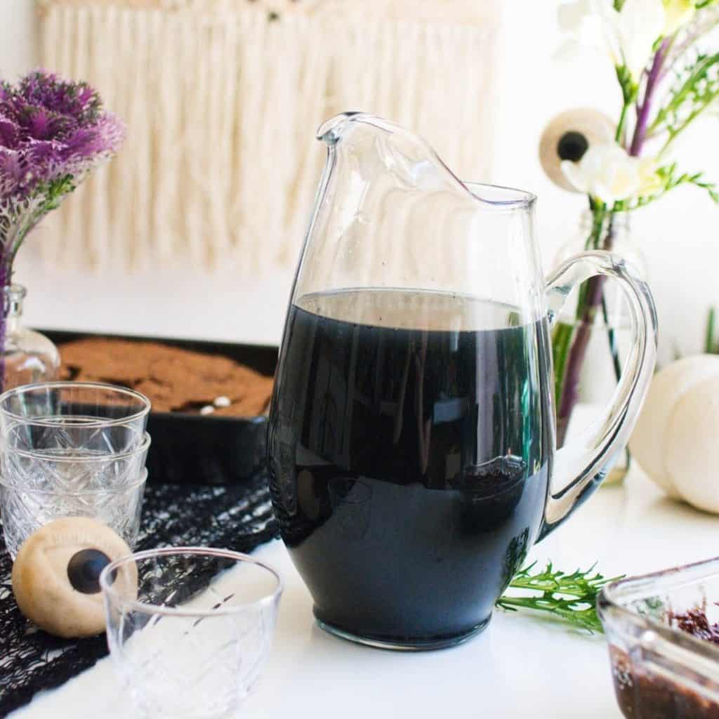 Close up of a black Vodka Punch for Halloween in a glass pitcher.