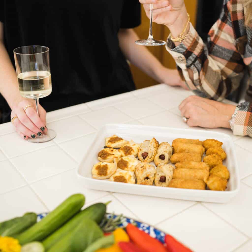 Woman with glasses of wine next to a tray of appetizers.