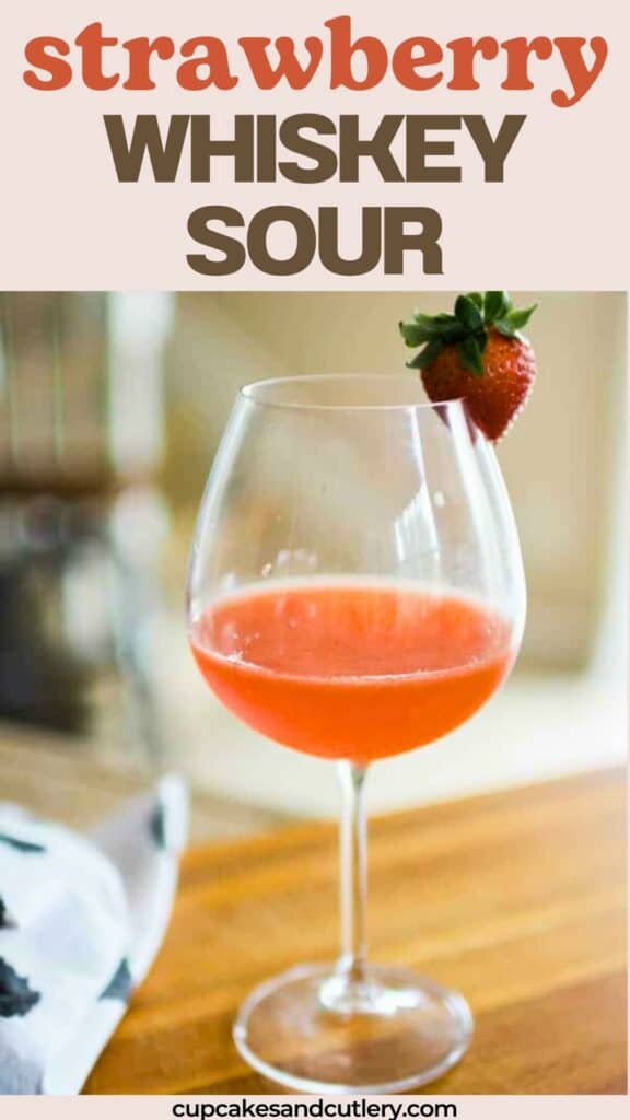 Strawberry whisky sour in a wine glass garnished with a fresh strawberry.