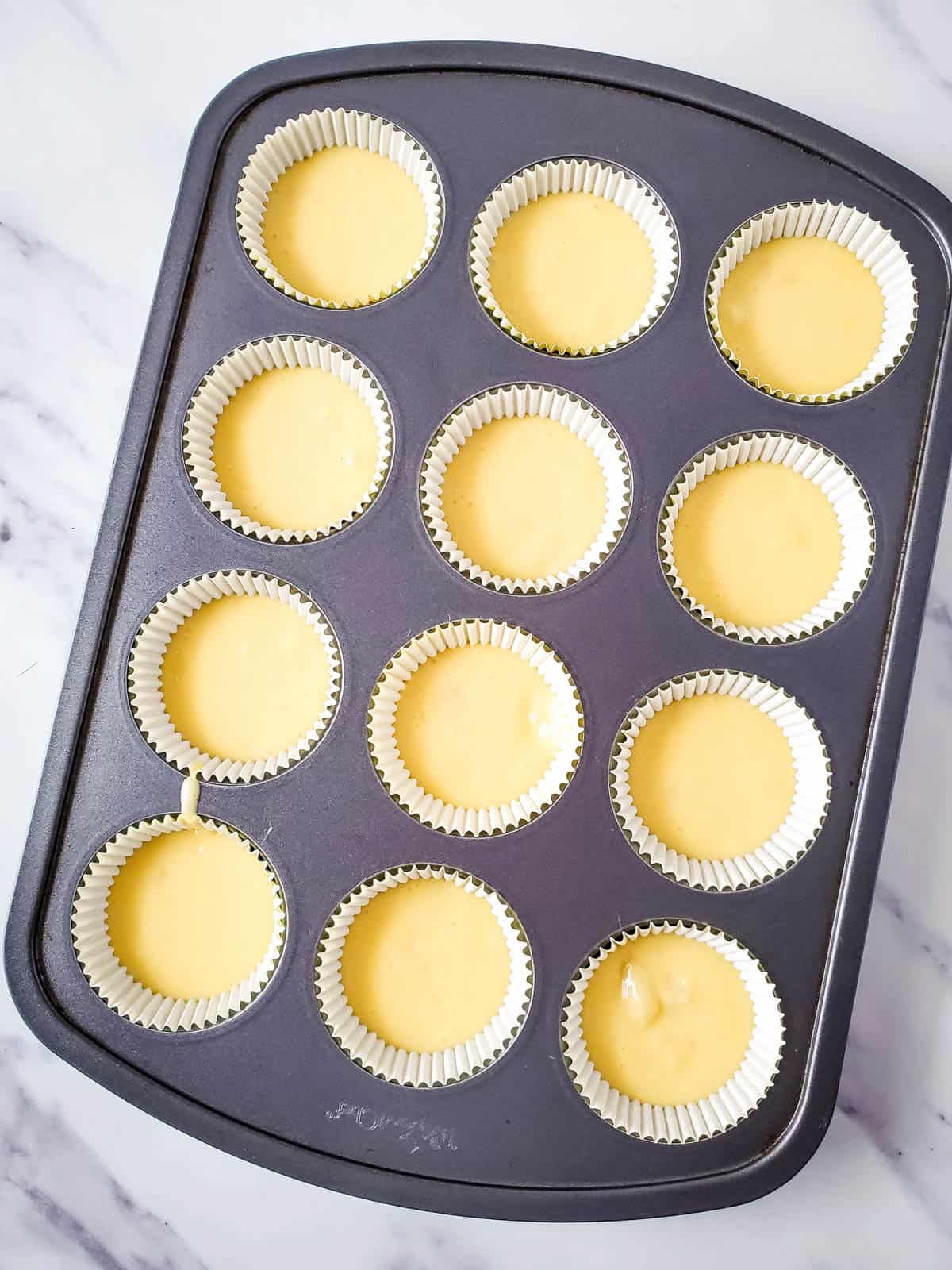 Cupcake batter in cupcake liners in a muffin tin.