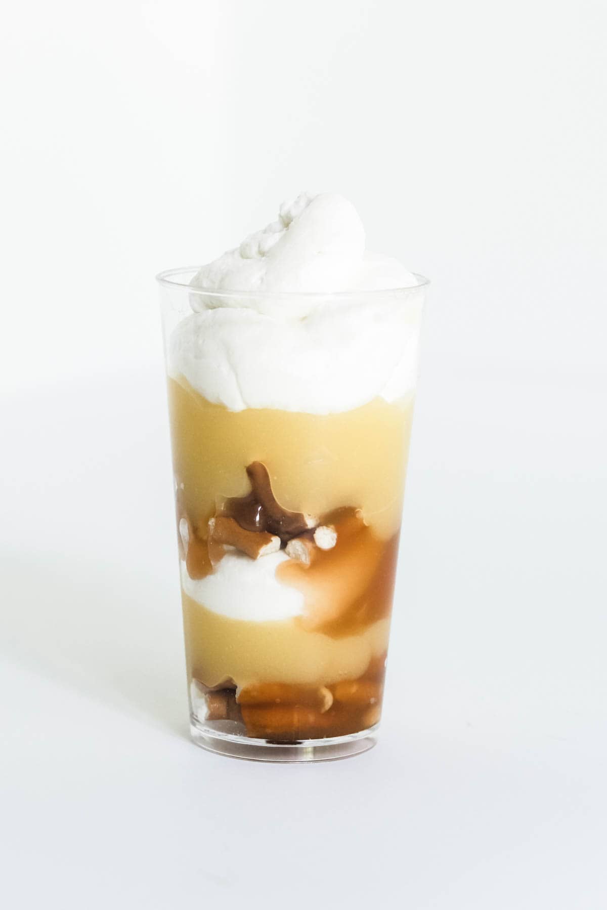 A mini trifle with layers of vanilla pudding, caramel, pretzels and whipped cream in a small glass.