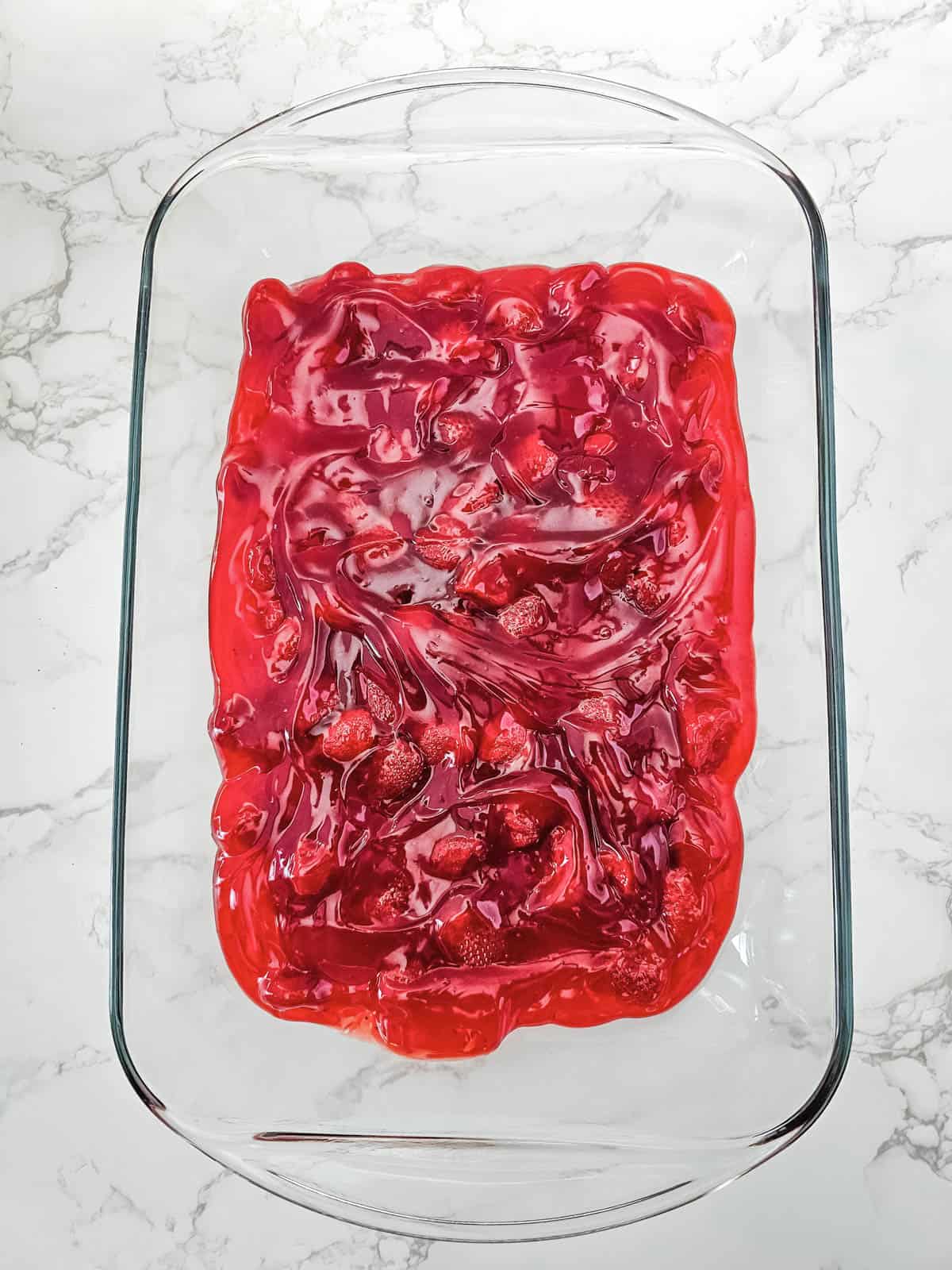 Strawberry pie filling spread evenly in a baking dish.