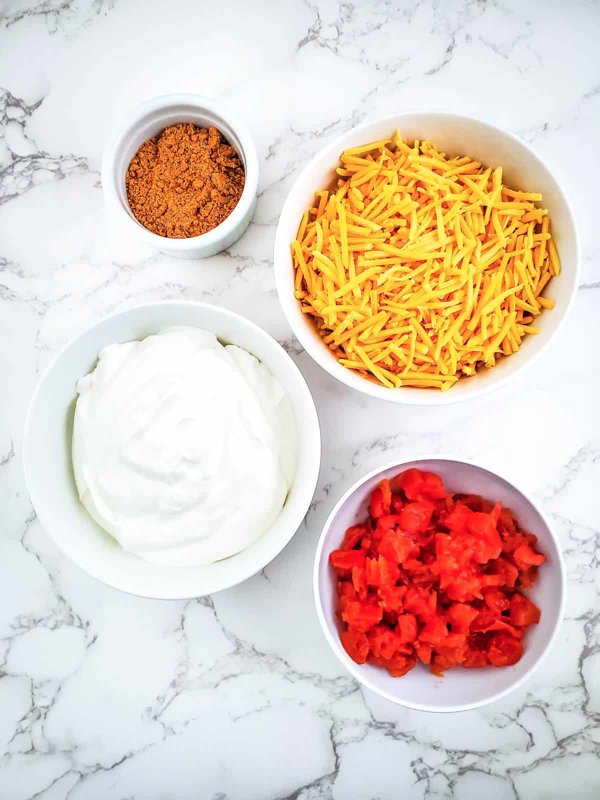 Ingredients for rotel taco dip includes cheddar cheese, rotel with red chiles, sour cream, and taco seasoning.