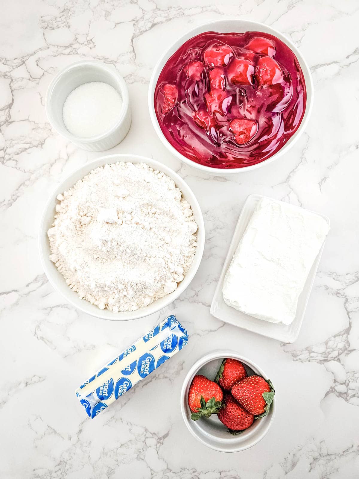 Ingredients for Strawberry Cheesecake Dump Cake on a marble countertop.