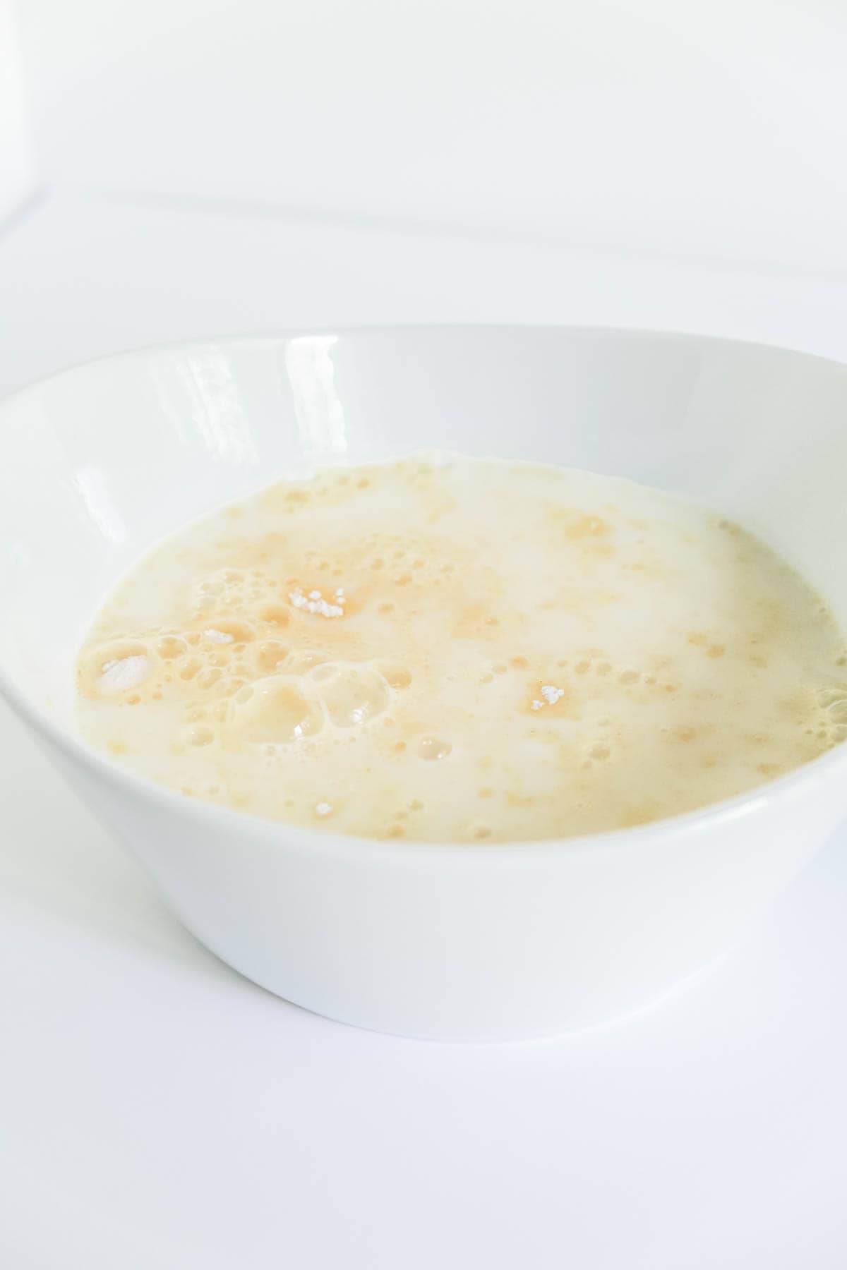 Vanilla pudding being made in a white bowl. 